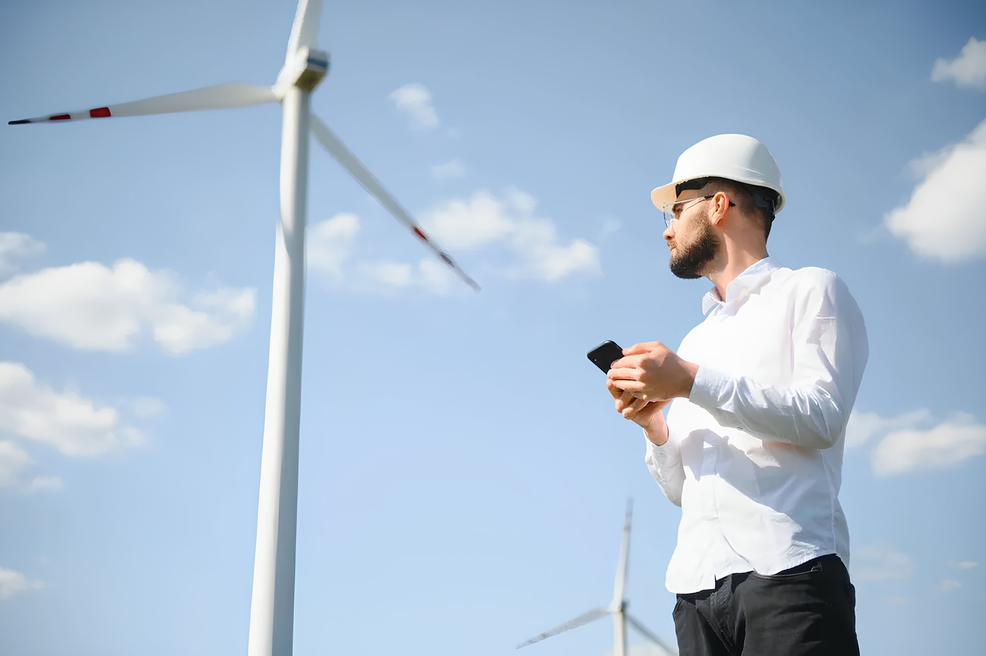 Field technician with smartphone near wind turbines – mobile-enabled field service management.-p-1080 (1)