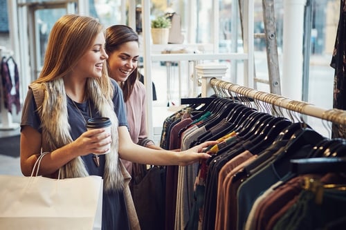 Smiling customers decide on purchases in retail boutiques while laughing 