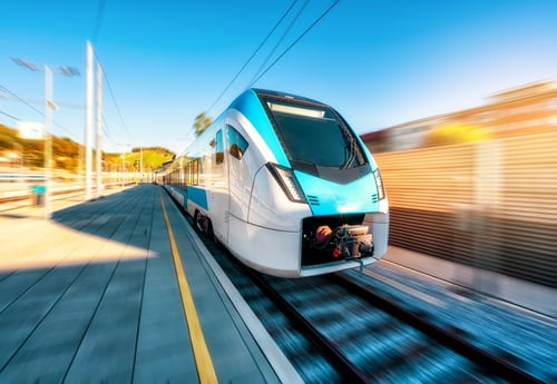 Combinación azul de pasajeros de alta velocidad en movimiento en la plataforma de la estación ferroviaria a pleno sol. 