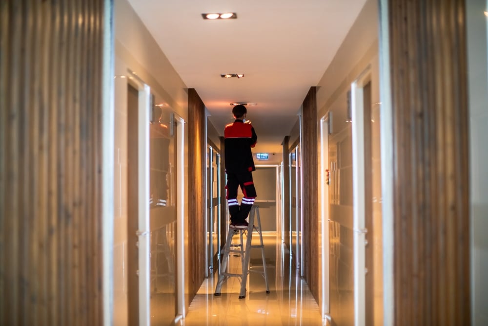 Technician working in a modern hallway – improving safety and compliance in building operations.